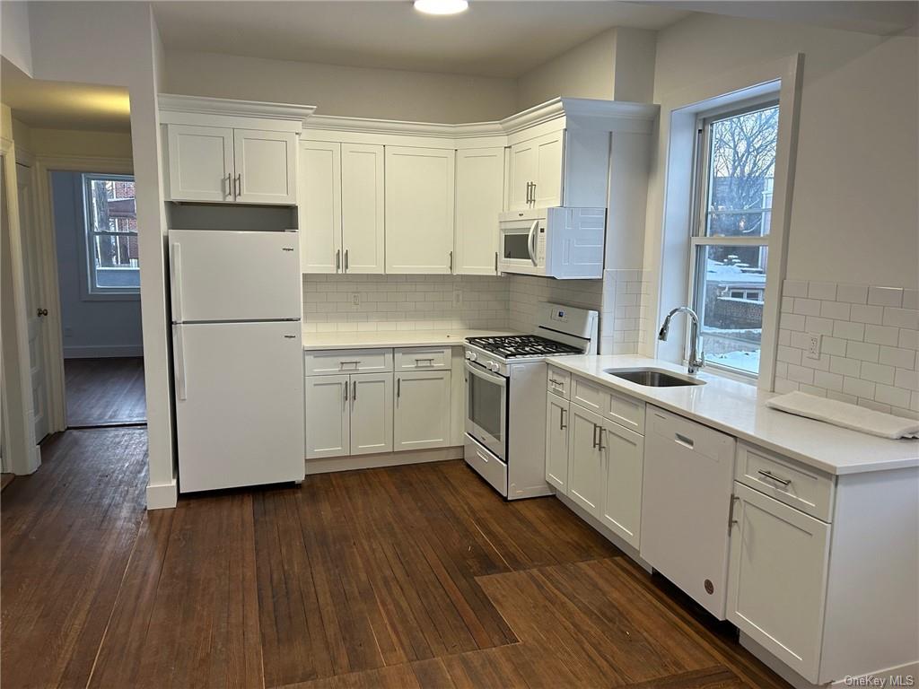a kitchen with a white cabinets a sink a window and stainless steel appliances