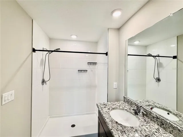 a bathroom with a granite countertop sink toilet and shower
