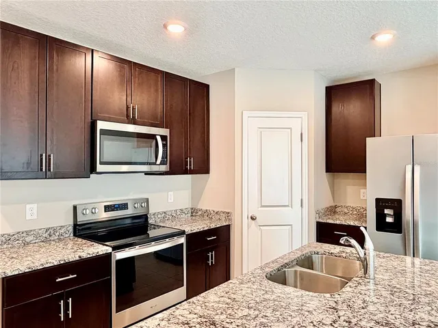 a kitchen with stainless steel appliances granite countertop a refrigerator and a stove top oven
