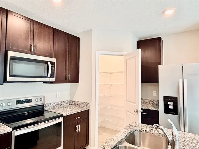 a kitchen with stainless steel appliances granite countertop a refrigerator and a stove top oven
