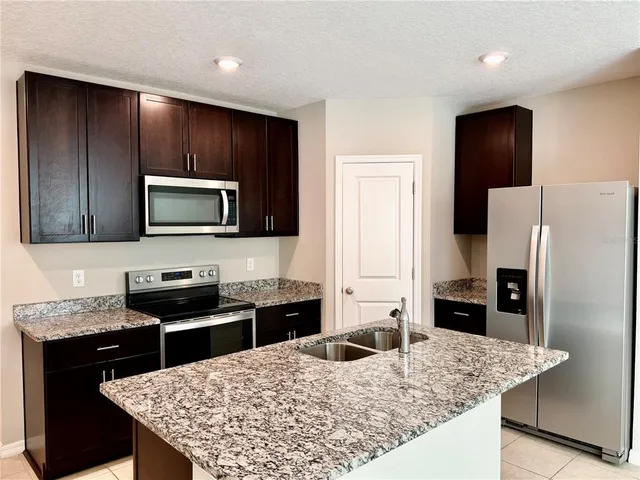 a kitchen with stainless steel appliances granite countertop a refrigerator a stove top oven a sink and dishwasher