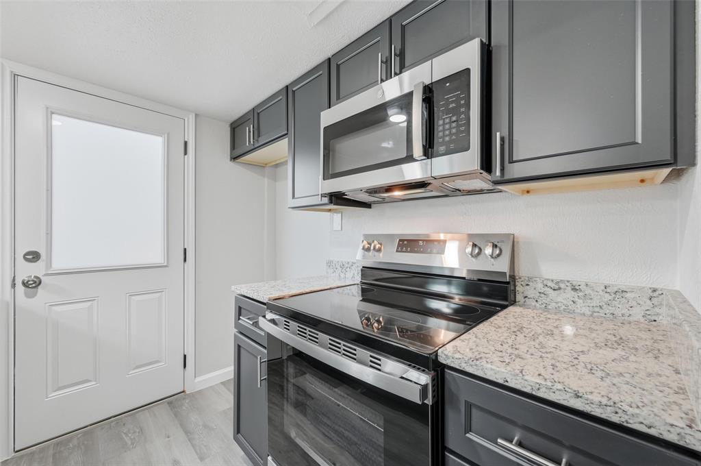 2702 Douglas Avenue, Unit 121 Dallas, TX 75219 - Photo 15 of 34 a kitchen with stainless steel appliances granite countertop white cabinets and a stove top oven