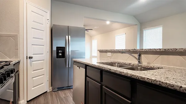a kitchen with granite countertop a sink and refrigerator