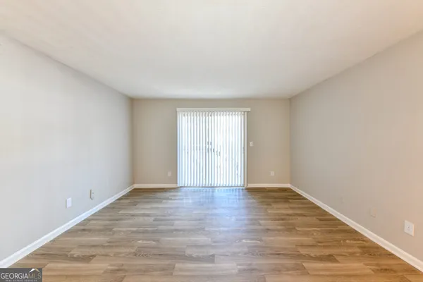 a view of an empty room with wooden floor and window