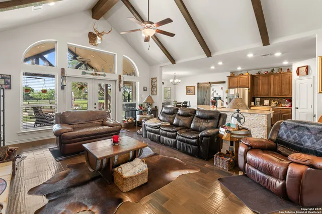 a living room with furniture kitchen view and a chandelier