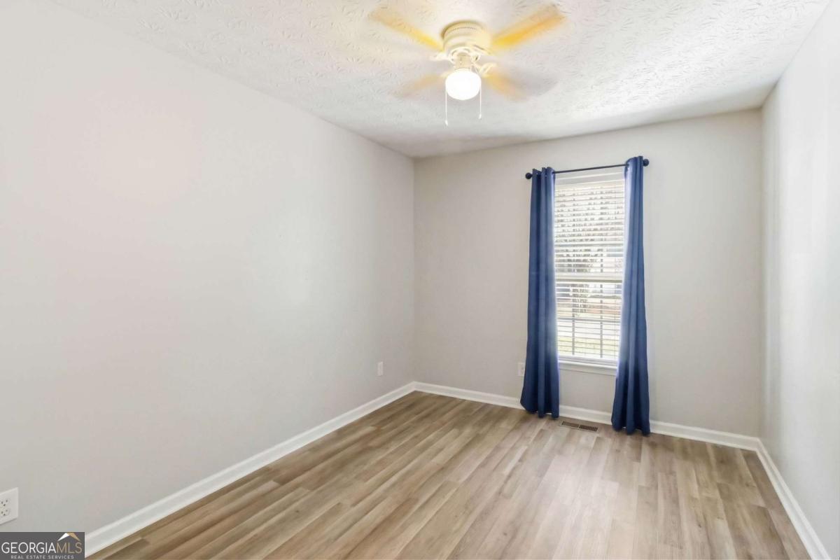 5559 Strathmoor Manor Circle Lithonia, GA 30058 - Photo 12 of 22 an empty room with wooden floor and windows
