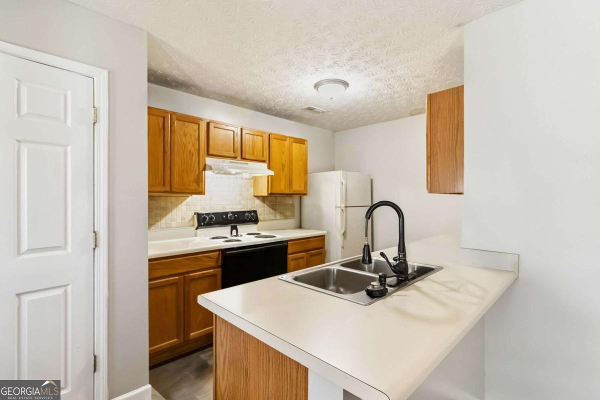 5559 Strathmoor Manor Circle Lithonia, GA 30058 - Photo 7 of 22 a kitchen with a stove a sink and a refrigerator