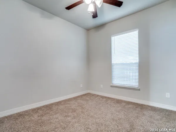 an empty room with a window and a ceiling fan