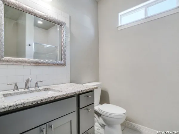 a bathroom with a granite countertop toilet sink and mirror