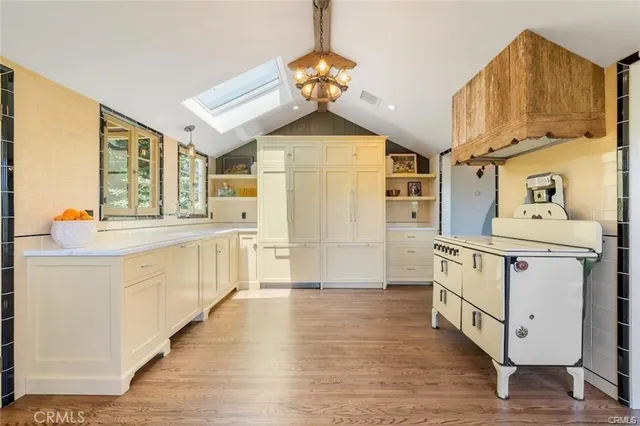 a open kitchen with stainless steel appliances granite countertop a stove a sink dishwasher and a refrigerator with wooden floor