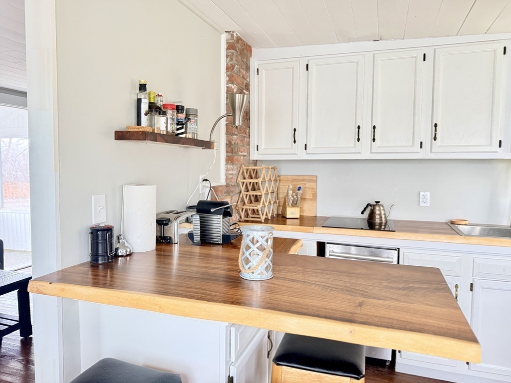 43 Pond Street, Unit 11 Dennis, MA 02670 - Photo 16 of 37 a kitchen with stainless steel appliances granite countertop a sink and white cabinets with wooden floor