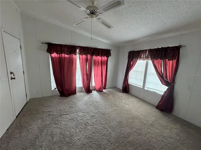 an empty room with windows and fan