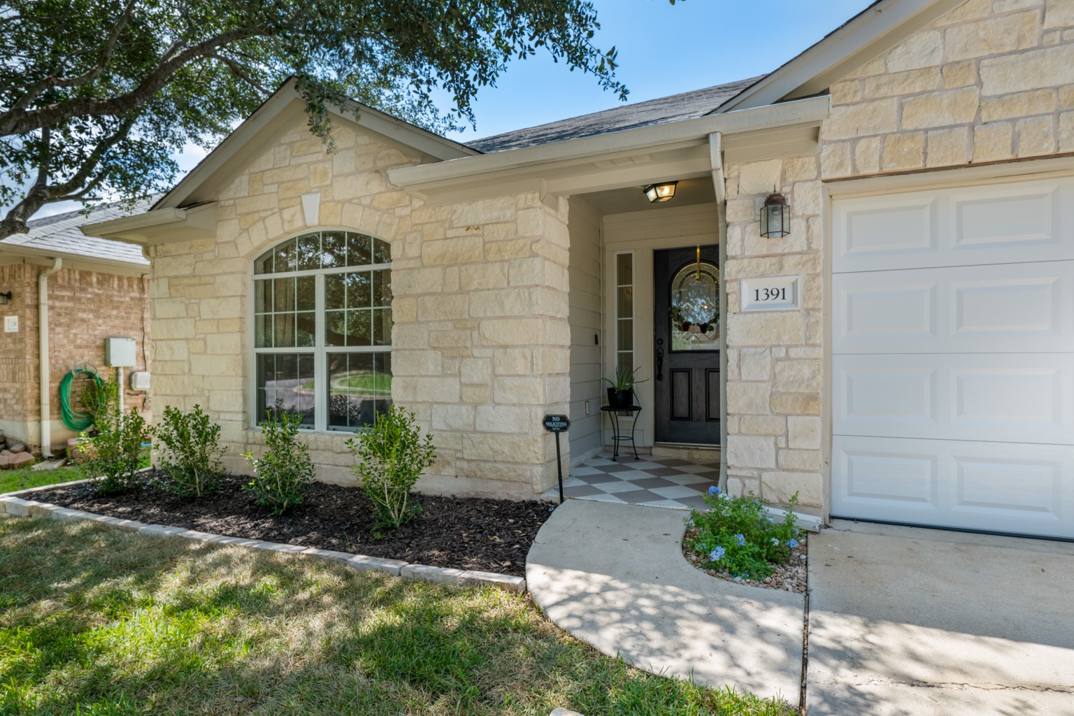 1391 Stone Rim Loop Buda, TX 78610 - Photo 2 of 35 A welcoming stone facade with an arched window and a covered front entry beckons.