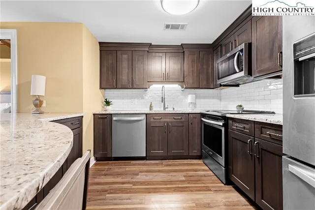 a kitchen with stainless steel appliances granite countertop a sink stove and microwave