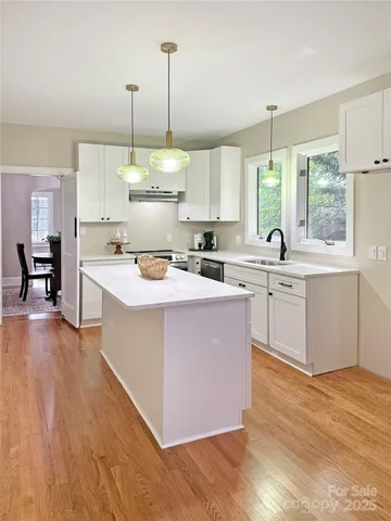 a kitchen with a stove a sink a kitchen island with a wooden floor and cabinets