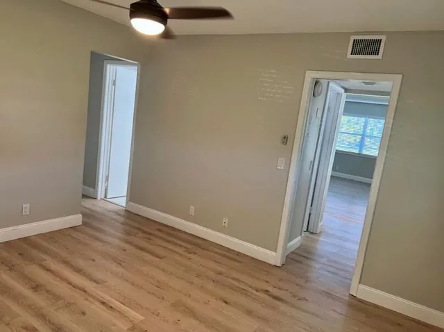 an empty room with wooden floor a ceiling fan
