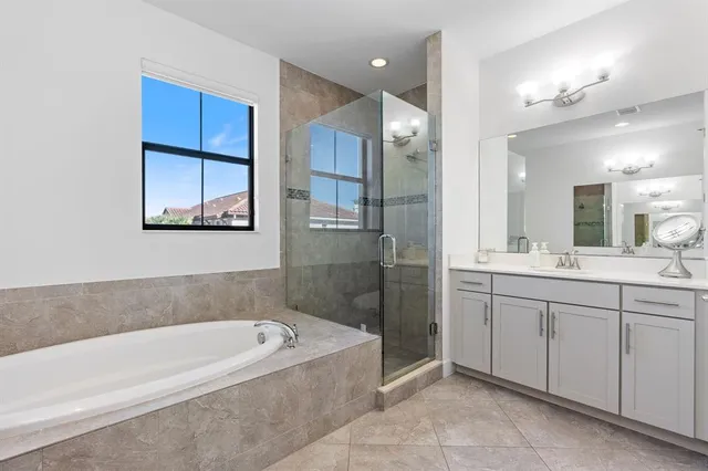 a bathroom with a bathtub a mirror a shower and vanity