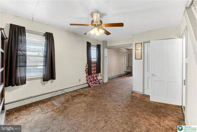 a view of an empty room with a ceiling fan and window