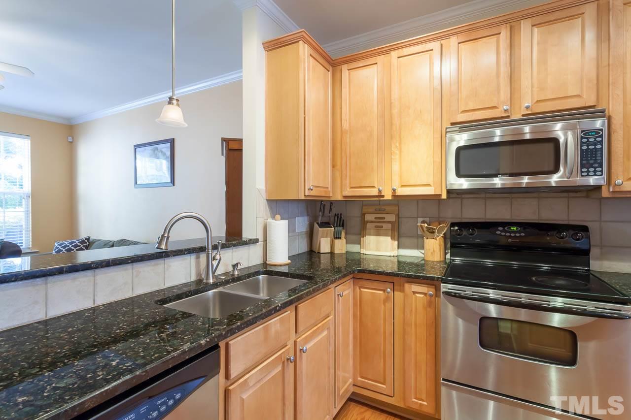 7815 Spungold Street Raleigh, NC 27617 - Photo 12 of 25 a kitchen with granite countertop a stove a sink and a microwave