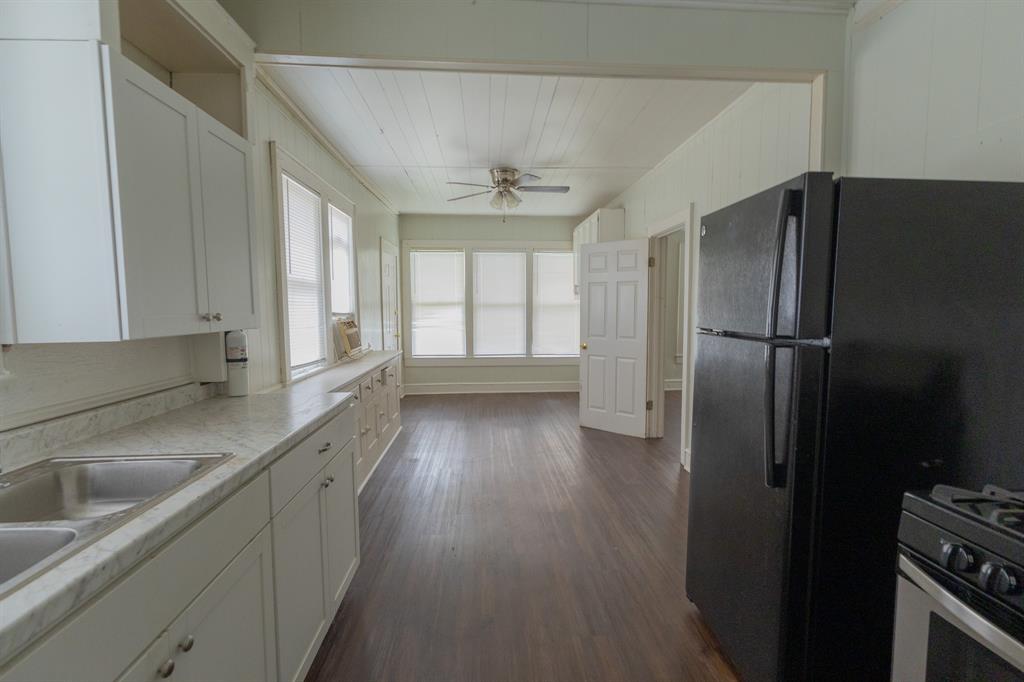 2913 Homan Avenue, Unit 2913 Waco, TX 76707 - Photo 14 of 16 Kitchen featuring white cabinetry, a double basin stainless steel sink, and wood-finish flooring
