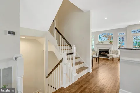 a kitchen with stainless steel appliances granite countertop a refrigerator a stove a sink dishwasher and white cabinets with wooden floor next to windows