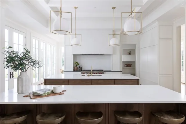 a kitchen with kitchen island stainless steel appliances a table chairs in it and wooden floor