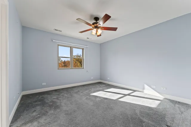 an empty room with windows and ceiling fan