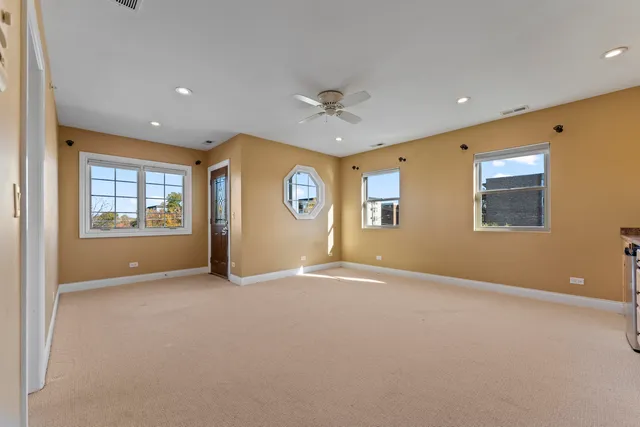 an empty room with windows and ceiling fan