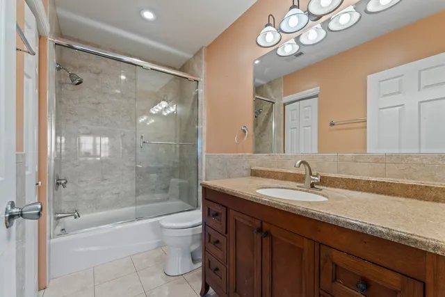 a bathroom with a granite countertop sink a toilet a mirror and shower