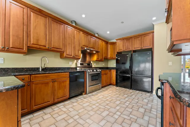 a kitchen with stainless steel appliances granite countertop a refrigerator sink and stove