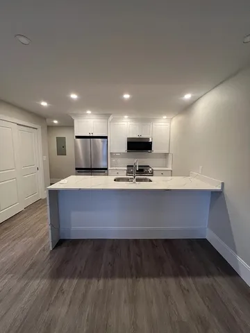 a large kitchen with stainless steel appliances wooden cabinets and a wooden floor