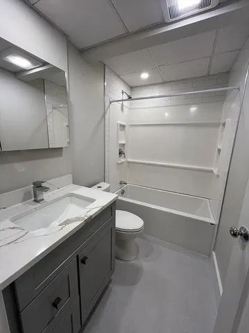 a bathroom with a granite countertop sink toilet and shower