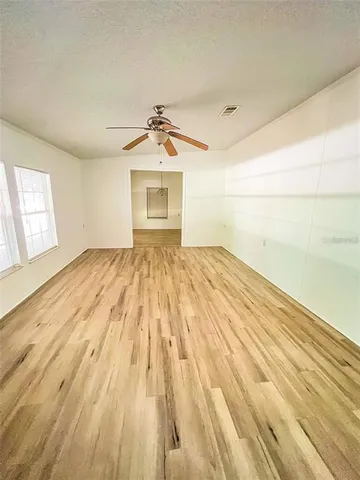 a view of empty room with wooden floor and fan