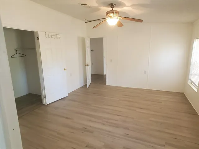 an empty room with wooden floor and fan