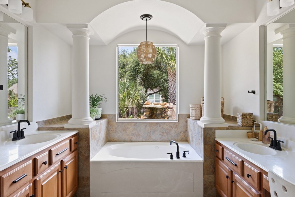 6704 Kiev Cove Austin, TX 78739 - Photo 19 of 37 Indulge in a relaxing soak within this primary bathroom, featuring a garden tub, dual vanities, and graceful columns.