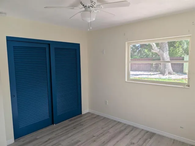 an empty room with wooden floor chandelier fan and windows