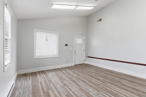an empty room with wooden floor and windows