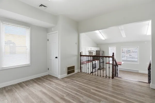 a view of a room with wooden floor kitchen view and windows