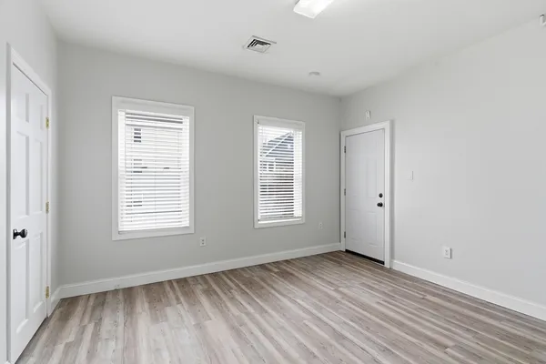 a view of an empty room with wooden floor and a window