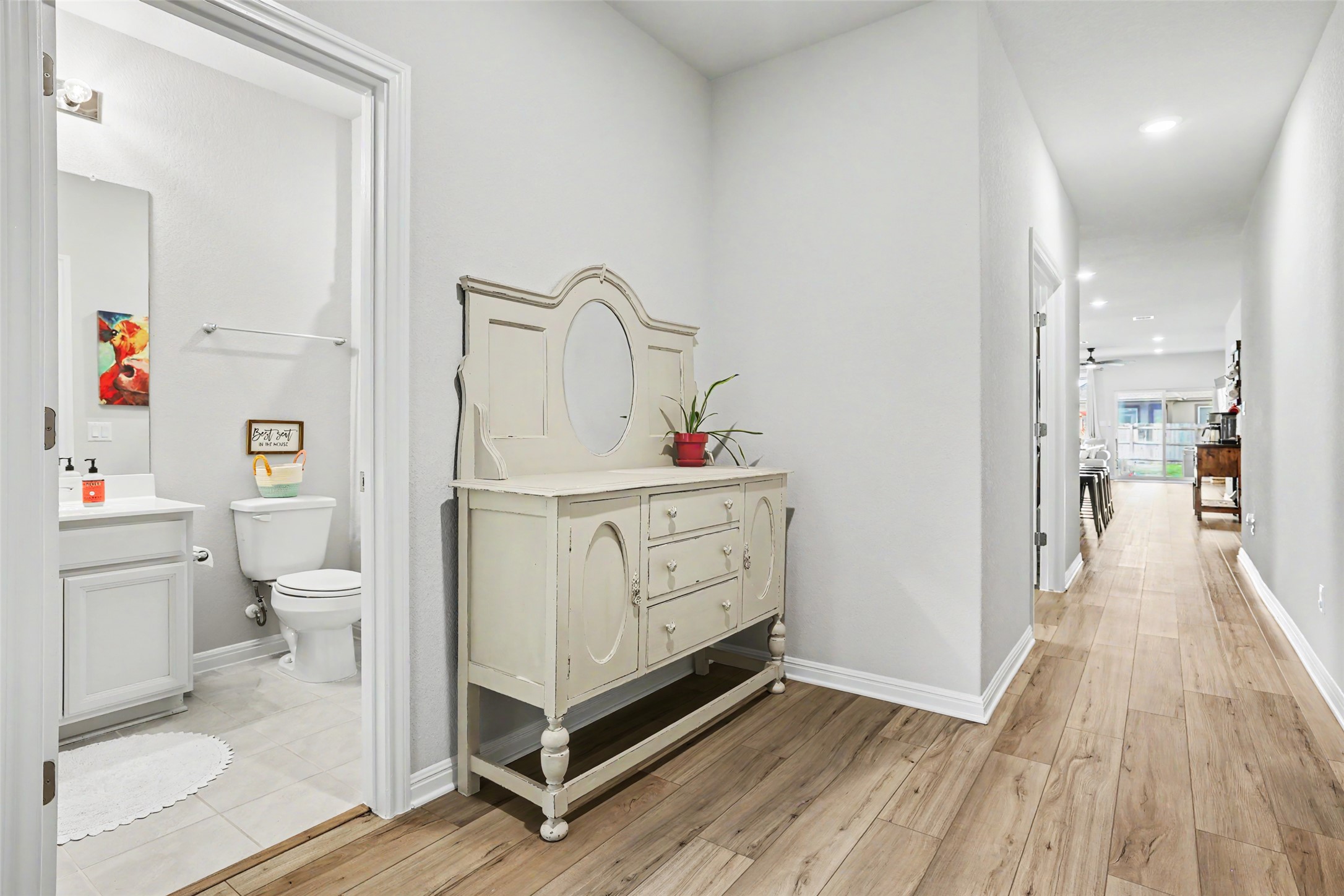 112 Rocking R Court Georgetown, TX 78633 - Photo 6 of 40 A graceful hallway with warm wood floors leads to an inviting bathroom and sun-filled living spaces.