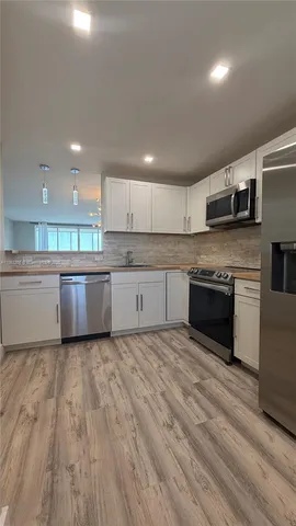 a large kitchen with stainless steel appliances granite countertop a stove a sink and a microwave