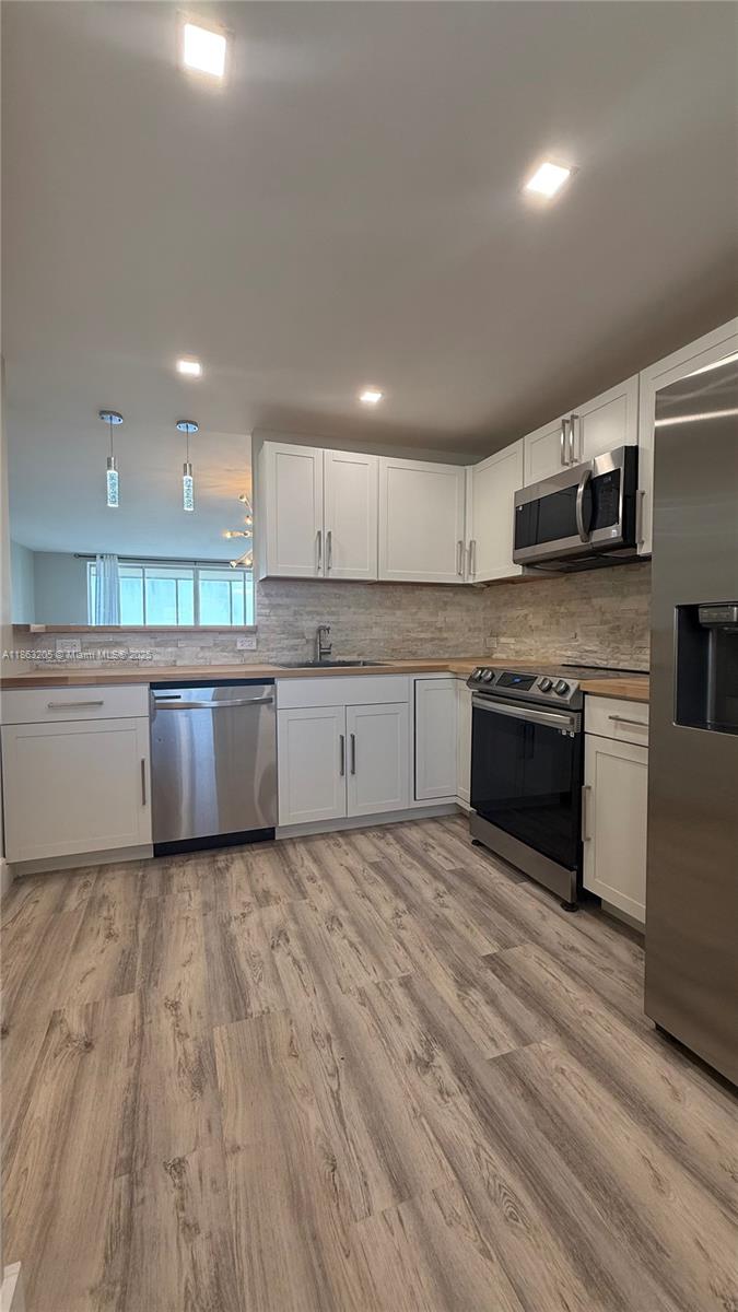 a large kitchen with stainless steel appliances granite countertop a stove a sink and a microwave