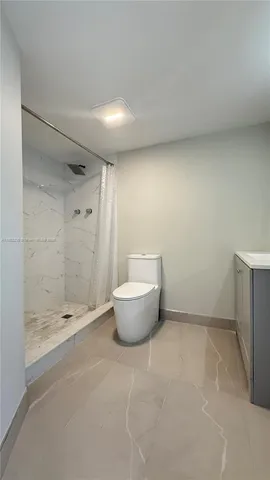 a bathroom with a granite countertop sink a toilet and shower
