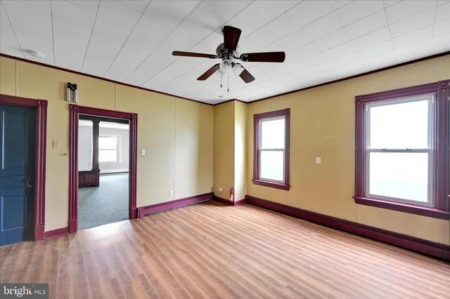 a view of an empty room with wooden floor and window
