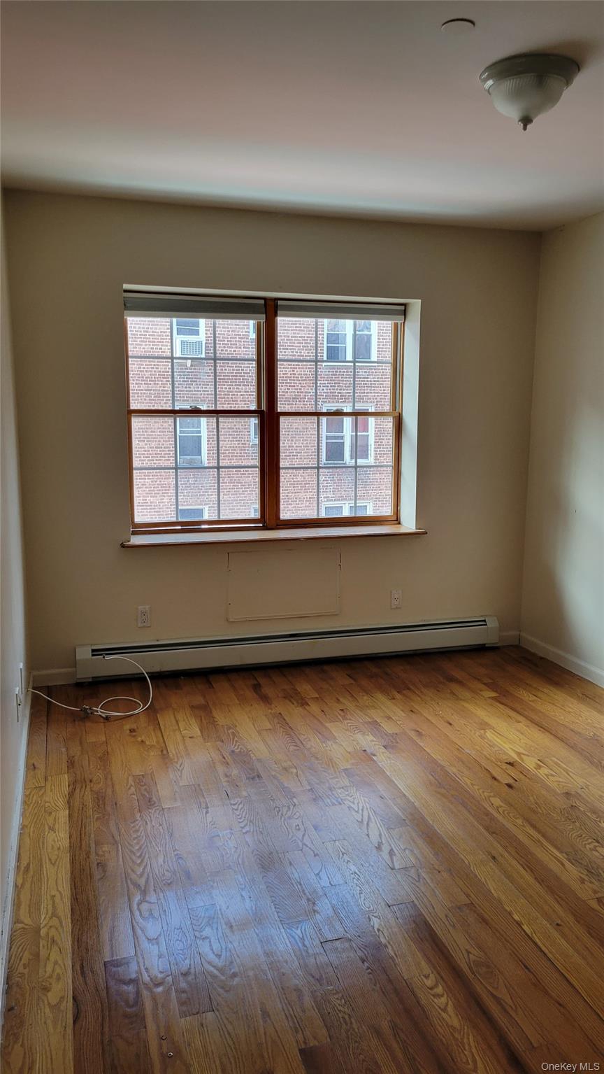 108-27 63rd Avenue, Unit 3B Queens, NY 11375 - Photo 12 of 17 an empty room with wooden floor and windows