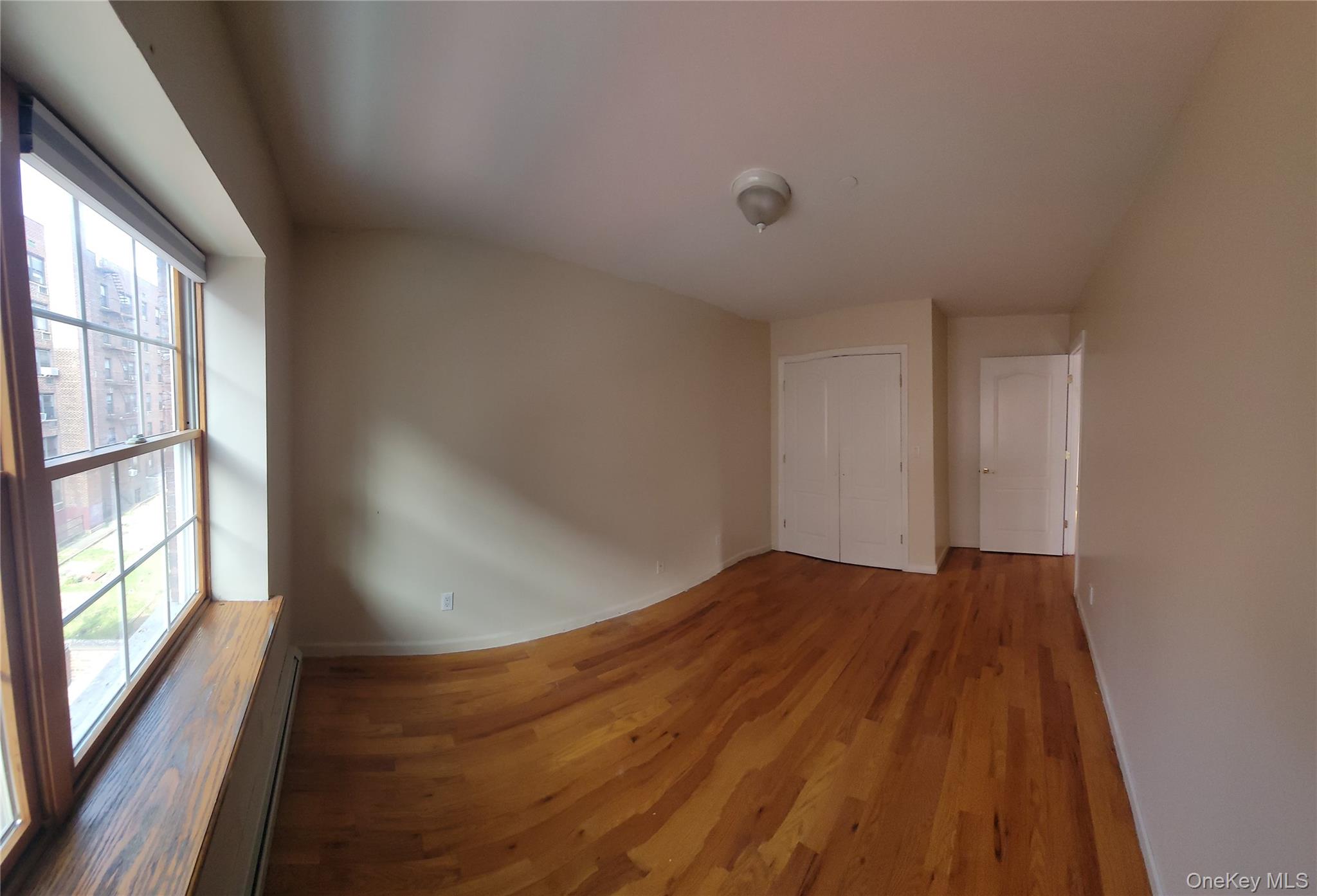 108-27 63rd Avenue, Unit 3B Queens, NY 11375 - Photo 14 of 17 wooden floor in an empty room with a window