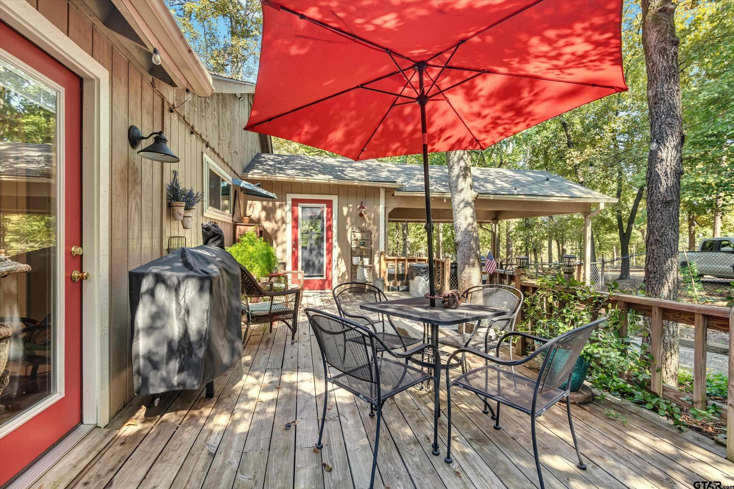 210 Magnolia Lane Holly Lake Ranch, TX 75765 - Photo 13 of 42 a view of a patio with table and chairs under an umbrella with wooden floor