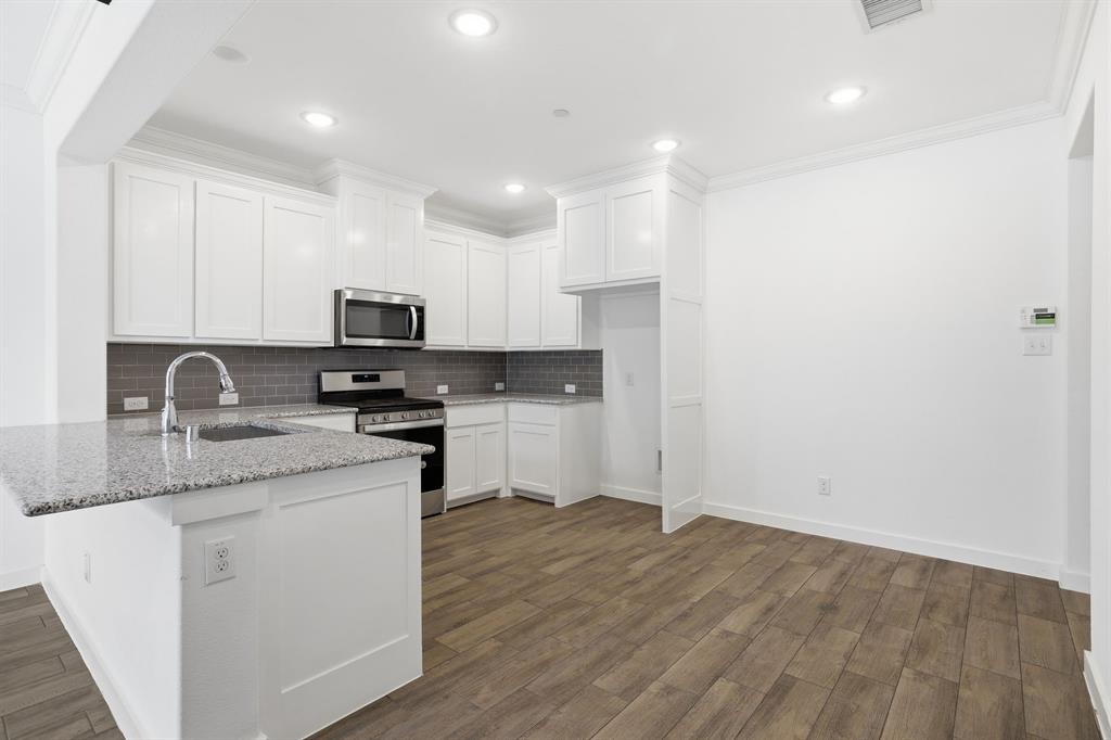 5832 Ridgeline Drive McKinney, TX 75070 - Photo 9 of 26 a kitchen with granite countertop white cabinets and appliances