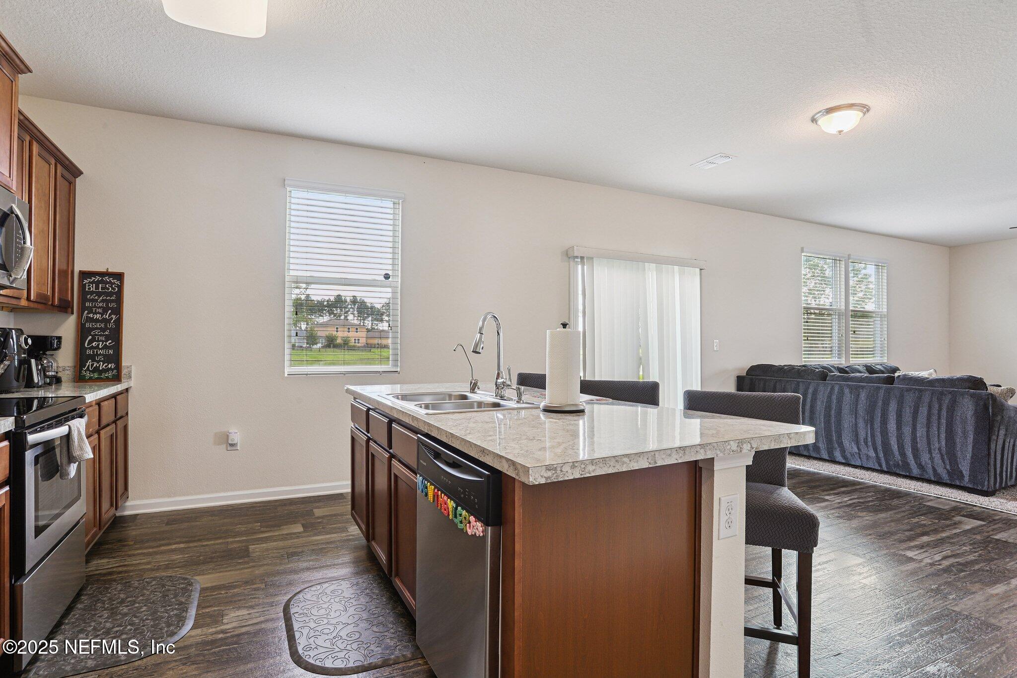 6829 Hanford Street Jacksonville, FL 32219 - Photo 11 of 24 a open kitchen with stainless steel appliances granite countertop a stove top oven a sink dishwasher and a refrigerator with wooden floor
