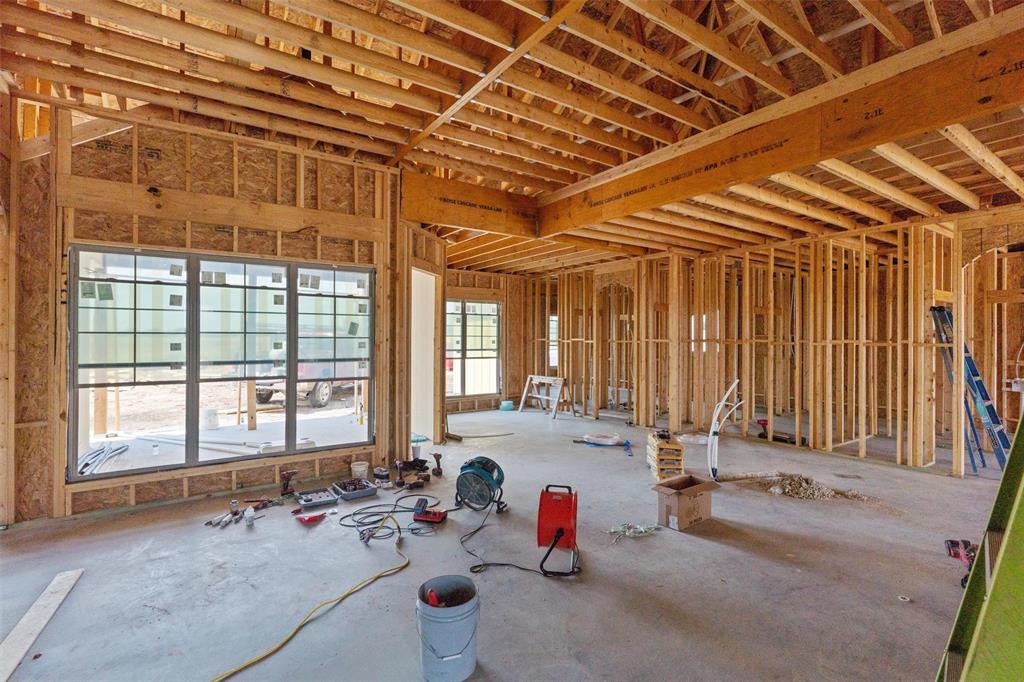 1405 Red Rock Road Hewitt, TX 76643 - Photo 19 of 25 Spacious open-concept layout with concrete slab flooring, wood framing, exposed wood ceiling joists, and large multi-pane windows